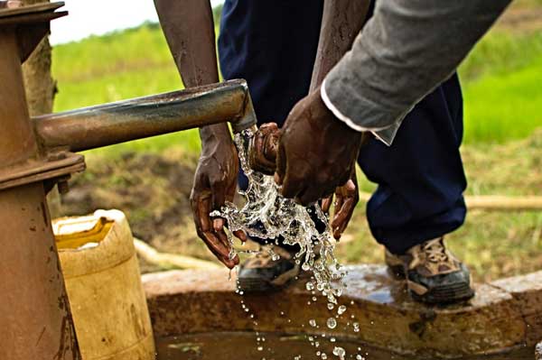 man drawing water out of a well provided by a nonprofit organization