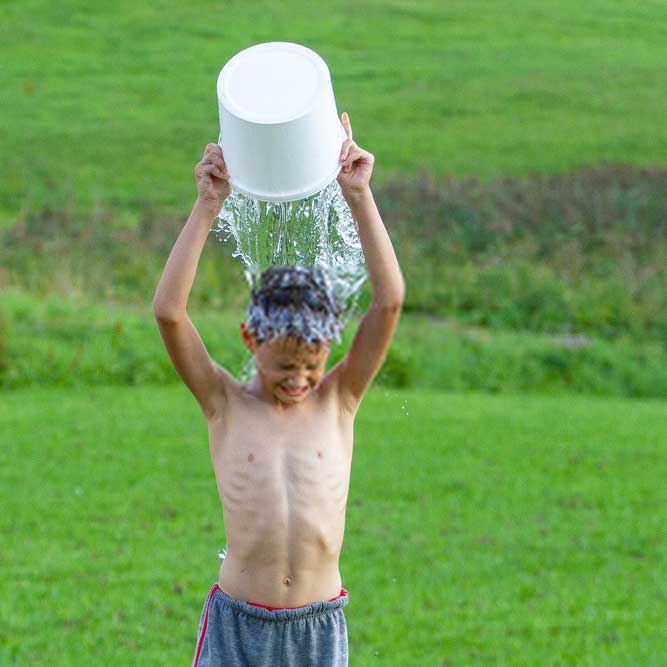 young boy pouring ice water for ice bucket challenge